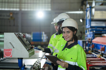 Young female engineer learning to run machinery at a factory with veteran engineers