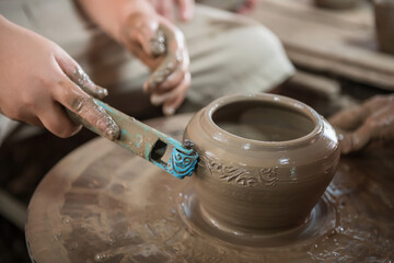 Kid make traditional thai floral pattern into clay pot, Koh Kret