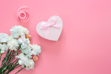 Bouquet of flowers, heart shaped gift box on pink background, flat lay.