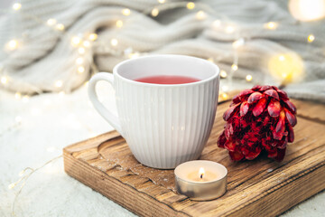 Cozy composition with a cup of red tea and an exotic flower in bed.