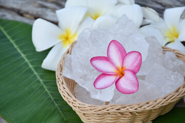Soft focus of purple plumeria flower and white alum cube on wicker basket, spa and skincare concept.