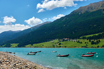 Lifeboats on the shore for personal rescue and training purposes. Watercraft in front of beautiful mountain landscape in the lake (Reschensee). Italy, Vinschgau, Giern.