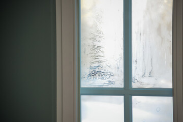 frozen icicle on a window pane on a cold winter day. sunlight shines through the glass in the room