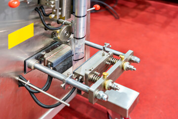 close up transparent envelope plastic pouch bag and horizontal heating sealing and cutting unit of continuous vertical automatic filling and packing machine for goods or food in industrial