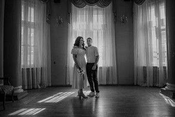 Happy newlywed couple holding hands on wooden ballroom balcony. Black and white photo