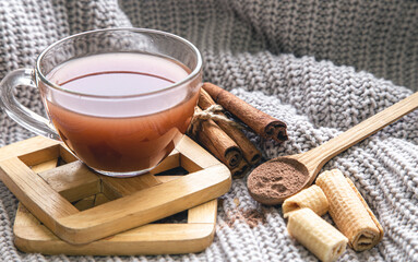 Composition with a cup of cocoa, cinnamon sticks and a knitted element.