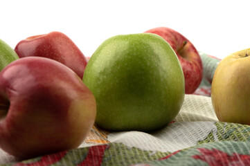 Close-up of ripe apples on a kitchen towel against a white background.