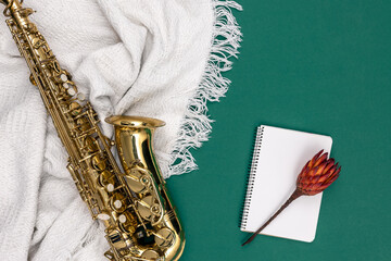 Saxophone on a green background and notepad, top view.