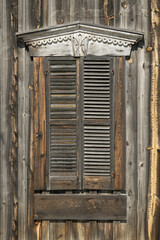 Old weathered closed wooden shutters on outside wall of building
