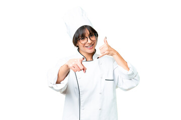 Young caucasian chef  woman over isolated chroma key background making phone gesture and pointing front
