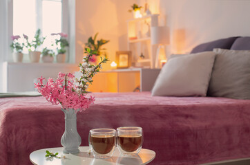 two thermo glasses  of coffee on white table in pink bedroom