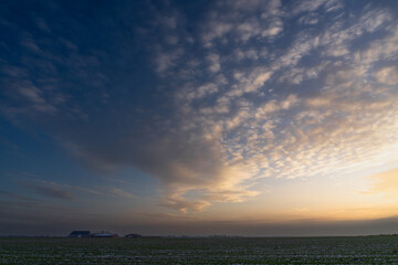 A band of scattered clouds fills the vast late afternoon sky over the flat lands of Denmark's west...