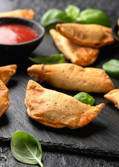 Freshly baked mini calzones with bolognese served on black slate board