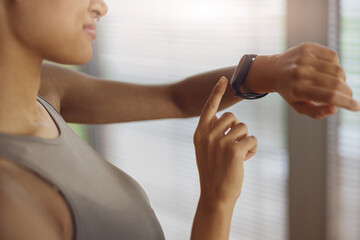 Fototapeta premium Smiling woman looking at sports watch and checking her performance after exercise at home