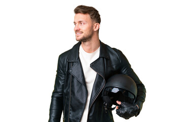 Young caucasian man with a motorcycle helmet over isolated chroma key background looking to the...