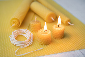 Natural rolled beeswax candles from pressed beeswax honeycomb sheet at home indoors. Hobby concept....