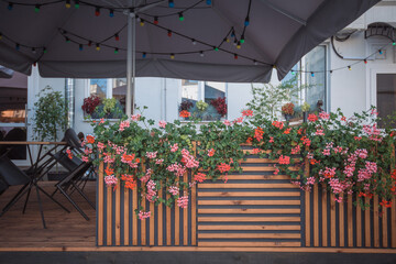 Exterior of a street cafe decorated with cute flowers and light garlands in the morning before opening.