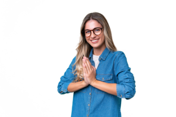Young Uruguayan woman over isolated background keeps palm together. Person asks for something