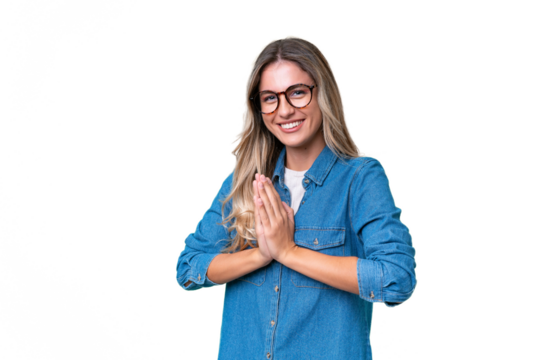 Young Uruguayan woman over isolated background keeps palm together. Person asks for something