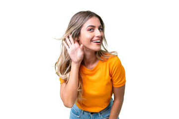 Young Uruguayan woman over isolated background listening to something by putting hand on the ear - obrazy, fototapety, plakaty
