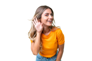 Young Uruguayan woman over isolated background listening to something by putting hand on the ear