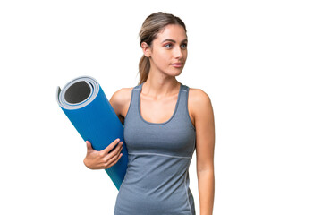 Pretty Young Uruguayan sport woman going to yoga classes while holding a mat over isolated...