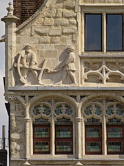 Bas relief sculpture of dockworkers holding an anchor on a medieval guild house in the port of Ghent