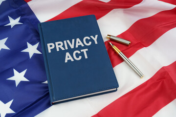 On the US flag lies a pen and a book with the inscription - PRIVACY ACT