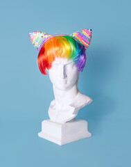 Male plaster head, classic roman style, decorated with funny party hair band. Creative colorful...
