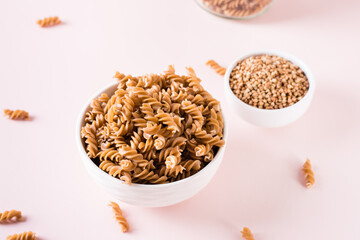 Bowls with raw buckwheat pasta and groats on the table. Alternative to wheat