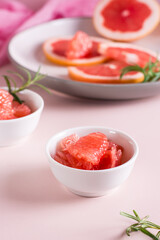 Peeled pieces of grapefruit and rosemary in a bowl on the table. Cocktail ingredients. Vertical view