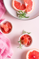 Juicy grapefruit slices and rosemary in a bowl on the table. Cocktail ingredients. Top and vertical view