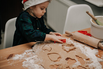 Dzieci wycinają wzroki z ciasta na świąteczne ciastka dla mikołaja - 553037471