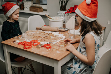 Dzieci wycinają wzroki z ciasta na świąteczne ciastka dla mikołaja - obrazy, fototapety, plakaty