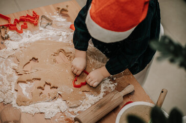 małe dziecko wycina wzorki w cieście na świąteczne pierniki
