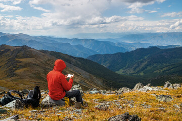 A man hiker studies a map of the area in his phone against the background of a beautiful mountain...