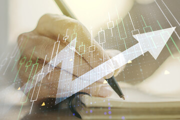 Abstract creative financial graph with upward arrow and woman hand writing in notebook on...