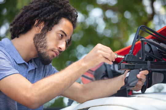 young man installing something on the car roof