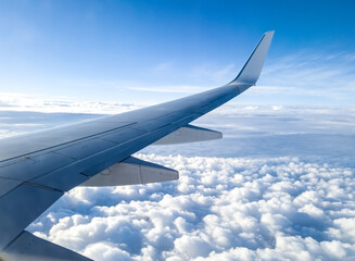 Obraz premium Airplane wing over clouds and sunny blue sky. Aerial view from an aircraft of an overcast sky with stratus cumulus until the horizon