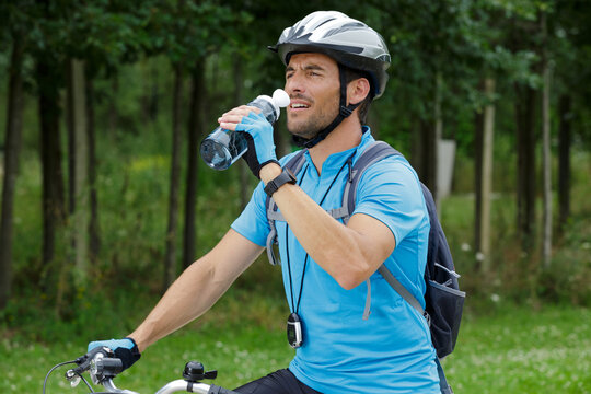 handsome man riding bike and drinking water resting - Powered by Adobe