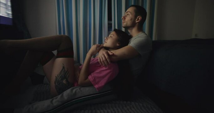 Couple watching TV together embraces together with love at home