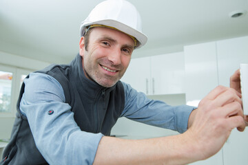 smiling man with adjusting central heating thermostat