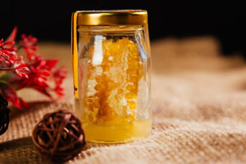 Jar of honey with honeycomb wax. Useful product of beekeeping.