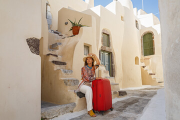 Young woman with a red suitcase on the background  Santorini, Greece