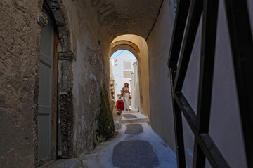 Young woman with a red suitcase walks through an architectural arch