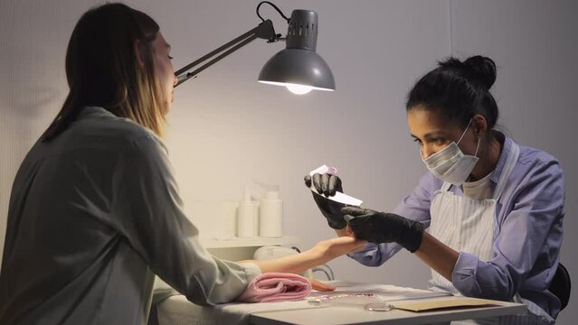 woman in nail salon does a manicure. hand and nail care, shellac coating. nail service master in beauty salon makes manicurist to client
