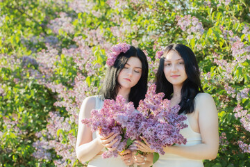 Fototapeta premium two young girls with blooming lilac in sunlight