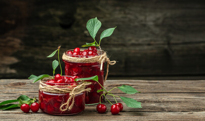 Jar of cherry jam and sour cherries. Berries cherry with syrup. Ripe ripe cherries. Sweet red cherries. Canned fruit on a wooden background