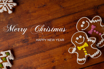 Gingerbread men with colorful icing on a brown wooden table top with various gingerbreads in the corners. Copy space. Top view.