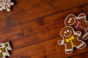 Gingerbread men with colorful icing on a brown wooden table top with various gingerbreads in the corners. Copy space. Top view.